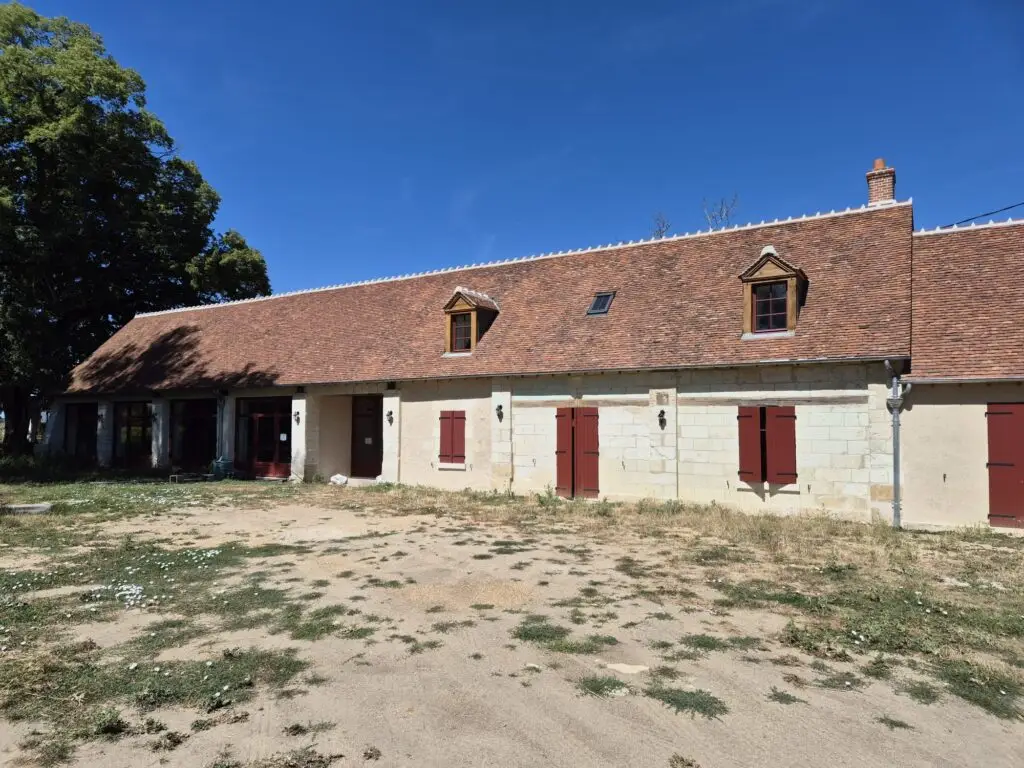 Longue maison en pierre aux volets rouges