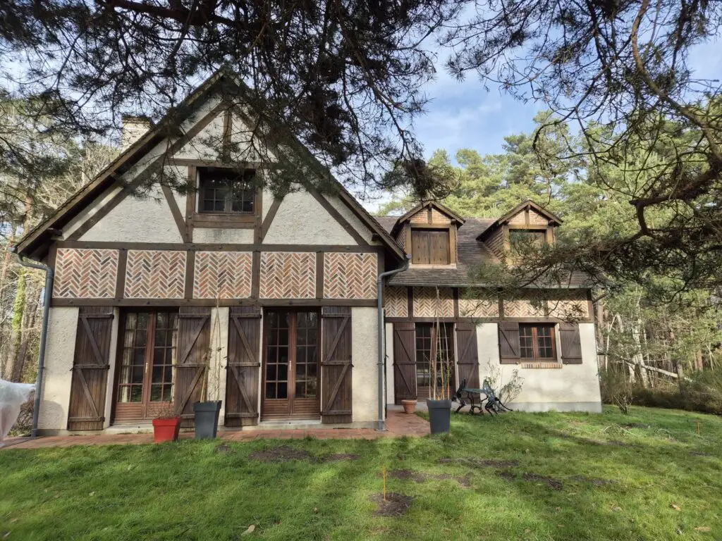 Maison à colombages entourée d’arbres et jardin